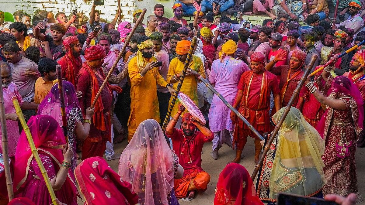 Crowd celebrates Holi as women beat men with sticks
